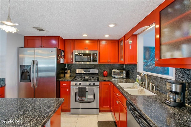 kitchen with sink, appliances with stainless steel finishes, decorative light fixtures, light tile patterned floors, and a textured ceiling