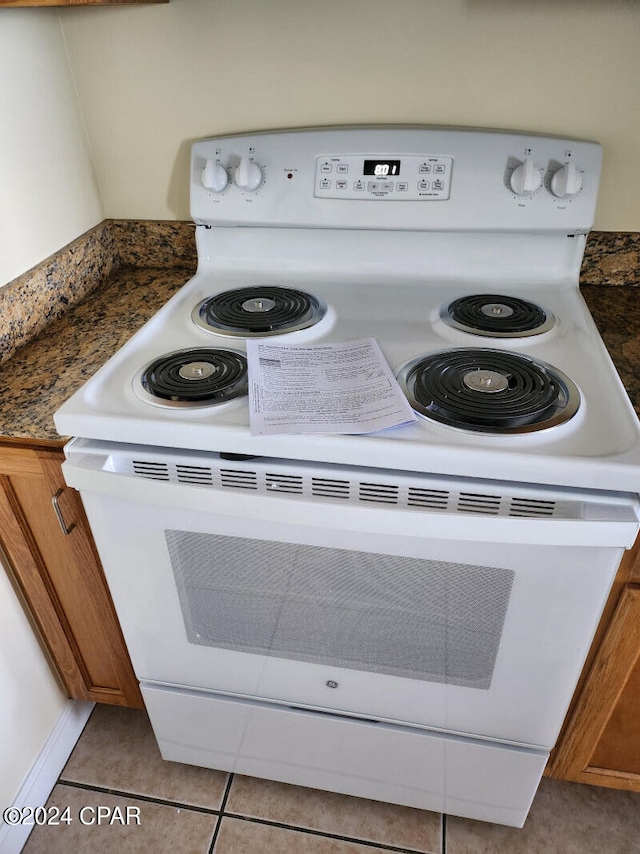 interior details with white electric stove and light tile flooring