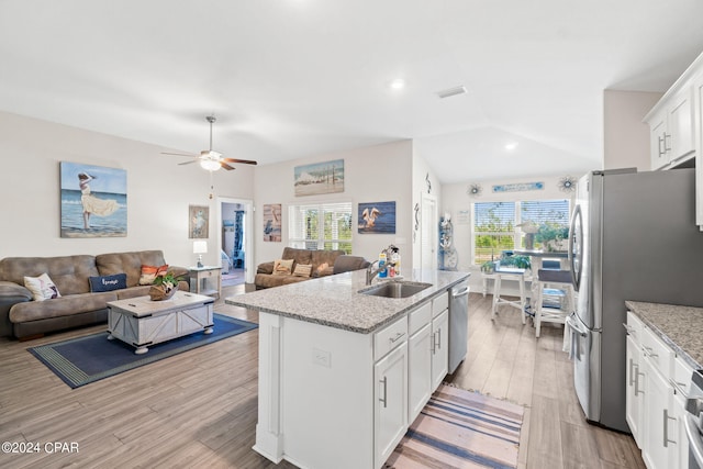 kitchen with white cabinets, vaulted ceiling, a wealth of natural light, and a center island with sink