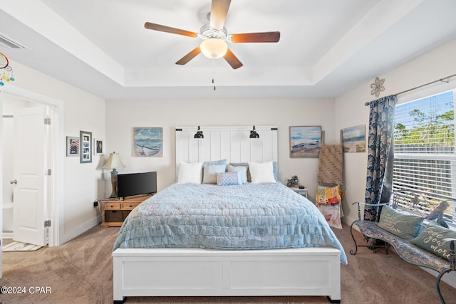 bedroom with carpet, ceiling fan, and a raised ceiling