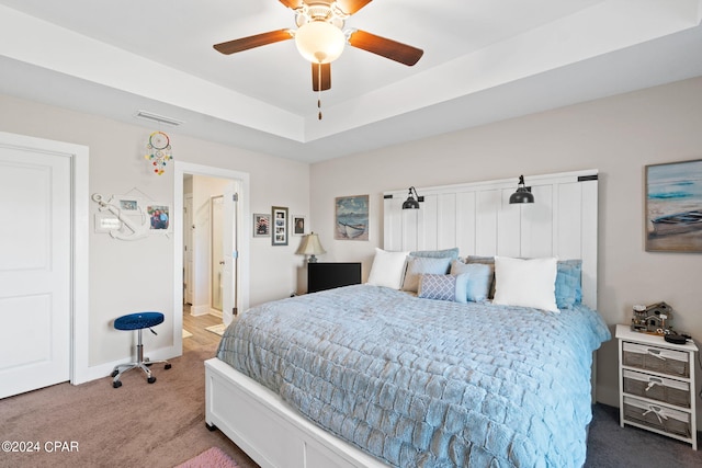 carpeted bedroom with ceiling fan and a raised ceiling