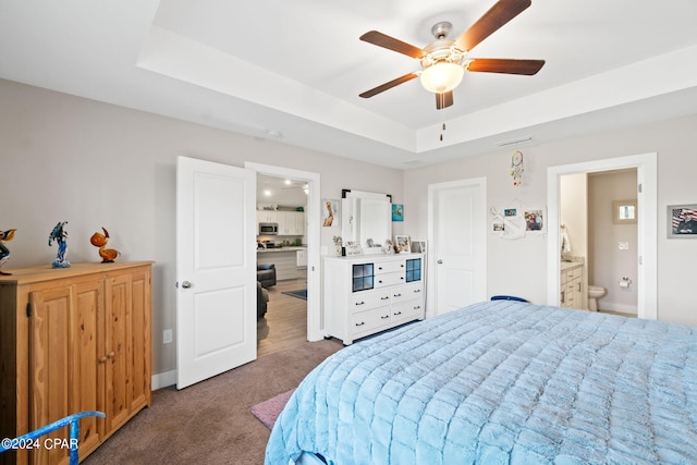 carpeted bedroom with a raised ceiling, ceiling fan, and ensuite bathroom