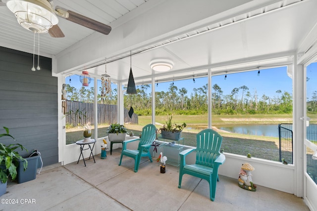 sunroom with ceiling fan and a water view