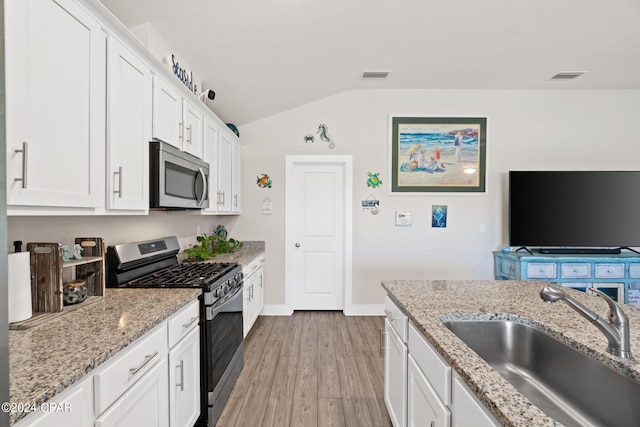 kitchen with white cabinetry, stainless steel appliances, sink, vaulted ceiling, and hardwood / wood-style flooring