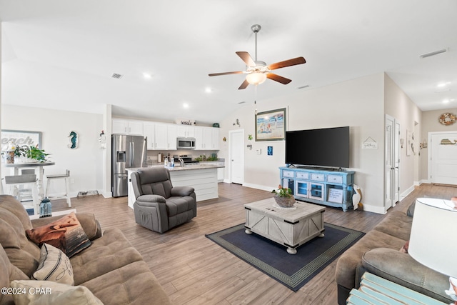 living room featuring lofted ceiling, ceiling fan, and light wood-type flooring