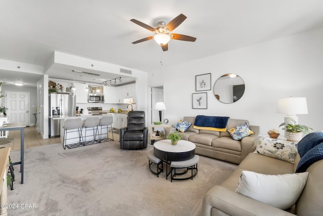 living room with a ceiling fan, visible vents, light carpet, and light tile patterned floors