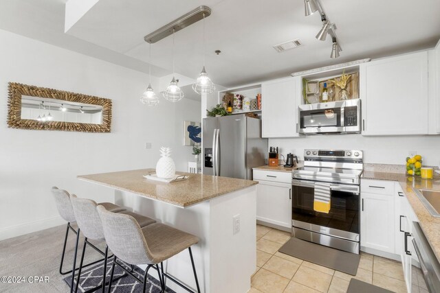 kitchen with stainless steel appliances, white cabinetry, a center island, and a kitchen bar