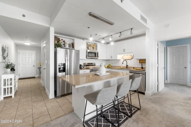 kitchen featuring visible vents, a kitchen breakfast bar, stainless steel appliances, white cabinetry, and a sink