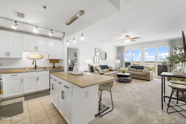 kitchen with a kitchen island, white cabinets, visible vents, and a sink