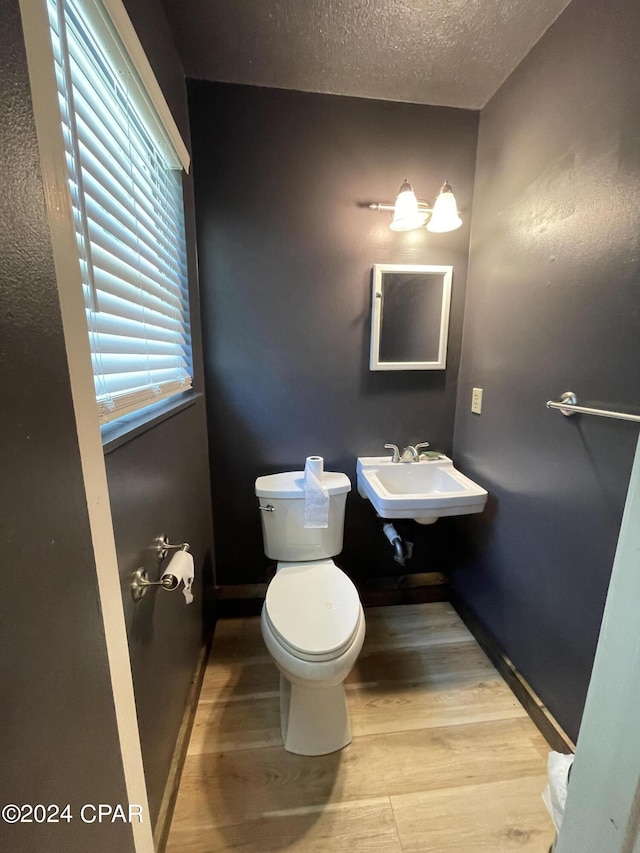 bathroom featuring a textured ceiling, toilet, sink, and wood-type flooring