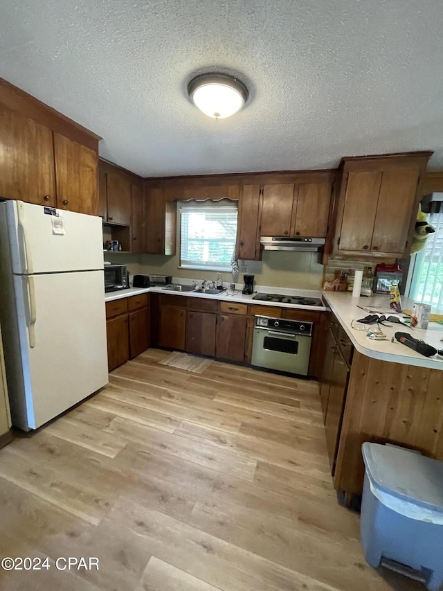 kitchen with stainless steel oven, a textured ceiling, electric stovetop, white fridge, and light hardwood / wood-style floors