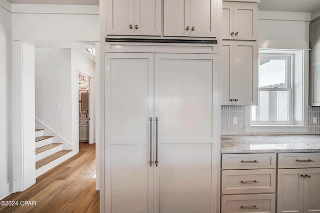 kitchen with light stone counters, backsplash, and light hardwood / wood-style floors