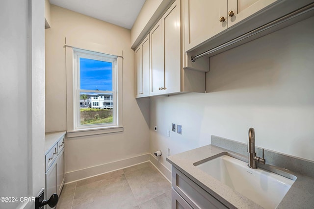 clothes washing area with cabinets, light tile patterned floors, hookup for a washing machine, electric dryer hookup, and sink