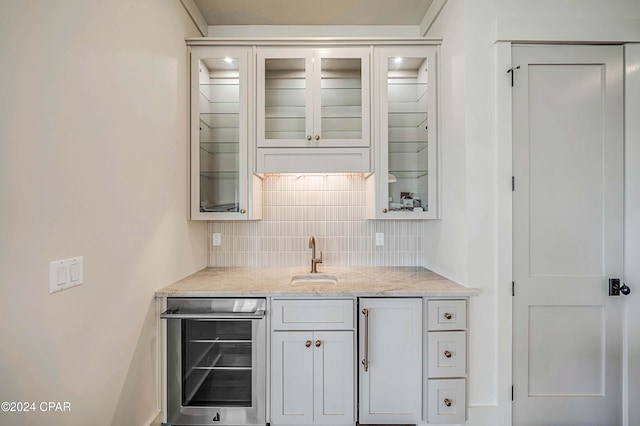 kitchen featuring tasteful backsplash, light stone countertops, sink, and beverage cooler