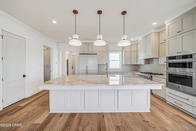 kitchen featuring light stone countertops, stainless steel appliances, sink, and hanging light fixtures