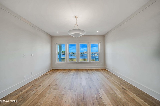 unfurnished dining area featuring crown molding and light wood-type flooring