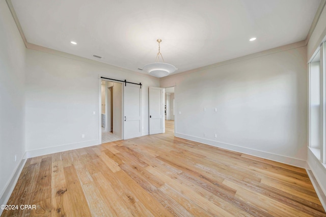 interior space with crown molding, a barn door, and hardwood / wood-style flooring