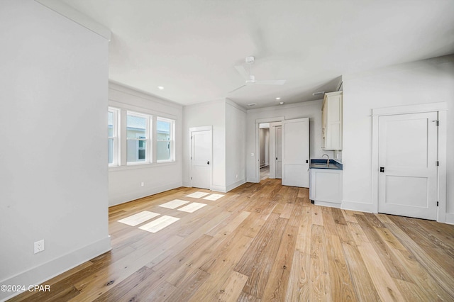 unfurnished living room featuring light hardwood / wood-style flooring, crown molding, and ceiling fan