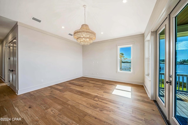 spare room with ornamental molding, an inviting chandelier, and hardwood / wood-style floors