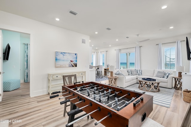 recreation room with a water view and light wood-type flooring