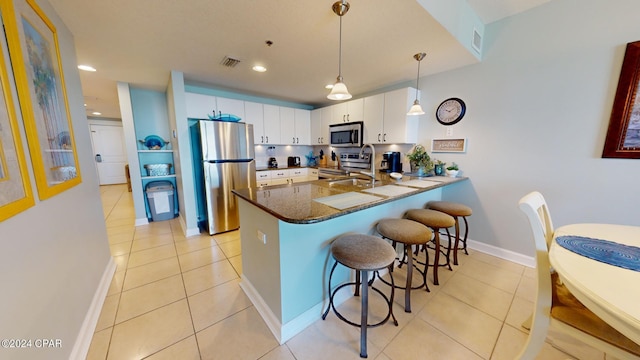 kitchen with visible vents, appliances with stainless steel finishes, a sink, a peninsula, and a kitchen bar