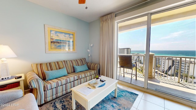 tiled living area featuring ceiling fan, a water view, and a view of the beach