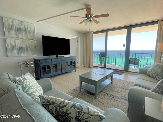 living room featuring ceiling fan, expansive windows, and a textured ceiling