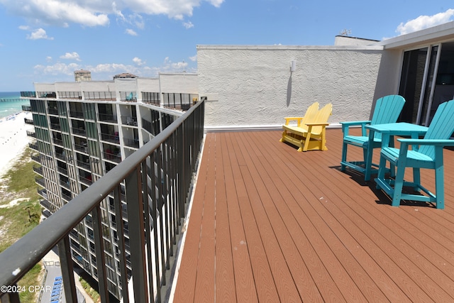 wooden terrace featuring a water view and a view of the beach