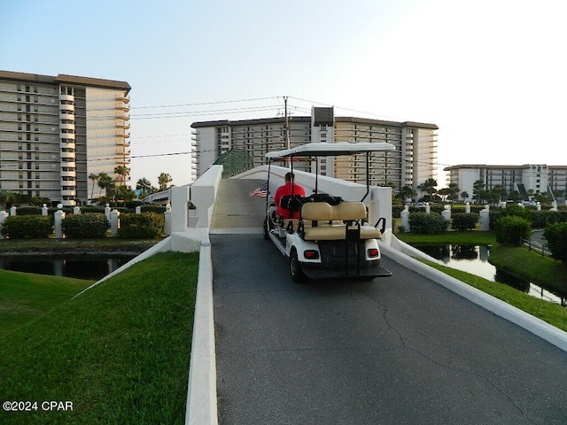 view of vehicle parking featuring a water view and a lawn