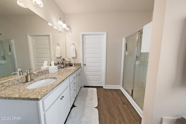 bathroom with hardwood / wood-style floors, an enclosed shower, and dual vanity