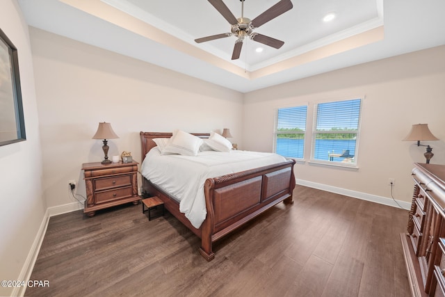 bedroom featuring a tray ceiling, ornamental molding, dark wood-type flooring, and ceiling fan