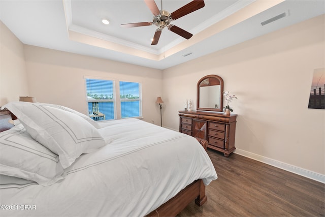 bedroom with a tray ceiling, crown molding, dark hardwood / wood-style floors, and ceiling fan