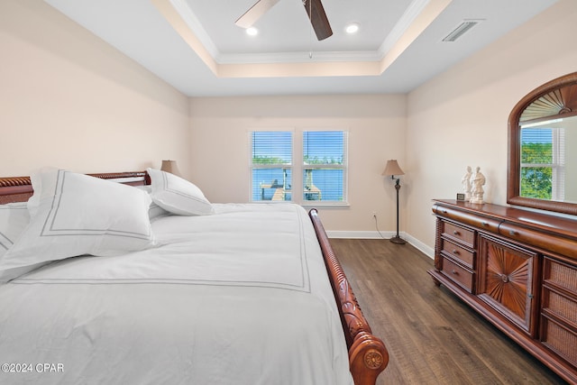 bedroom with ceiling fan, dark hardwood / wood-style flooring, a tray ceiling, and crown molding