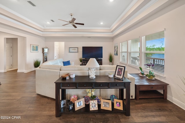 living room with dark hardwood / wood-style floors, ceiling fan, crown molding, and a raised ceiling