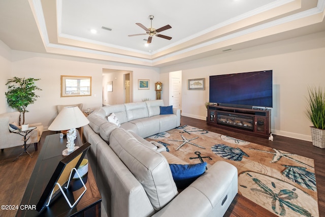 living room featuring ceiling fan, a raised ceiling, ornamental molding, and wood-type flooring