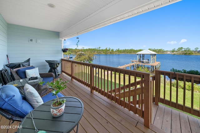 wooden deck featuring a boat dock, a water view, and a yard