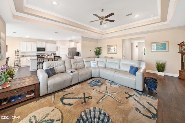 living room featuring a raised ceiling, ornamental molding, ceiling fan, and dark hardwood / wood-style floors