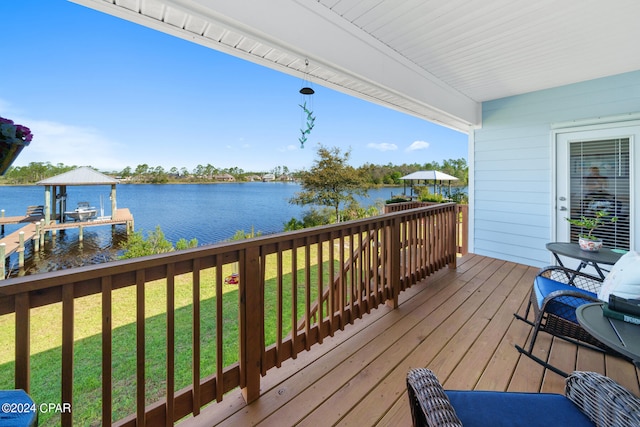 deck featuring a boat dock, a water view, and a lawn