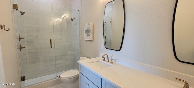 bathroom with vanity, toilet, and a shower with door