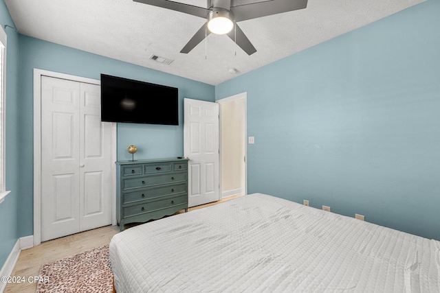 bedroom featuring a textured ceiling, light hardwood / wood-style flooring, a closet, and ceiling fan