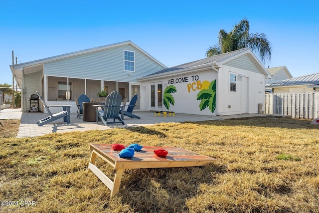 rear view of property featuring a sunroom, a patio area, and a yard