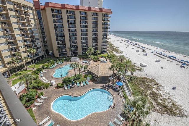 view of swimming pool with a patio area, a beach view, and a water view