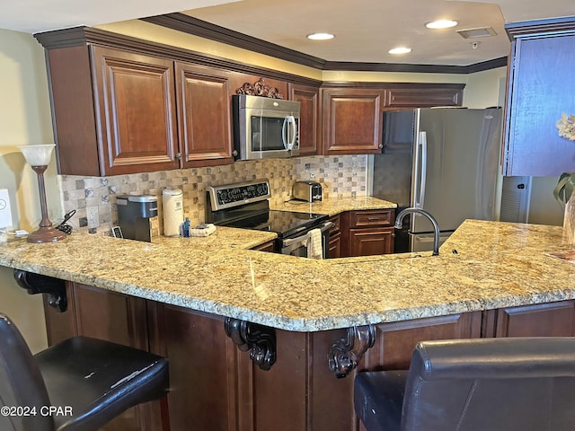 kitchen featuring stainless steel appliances, decorative backsplash, a kitchen breakfast bar, and kitchen peninsula