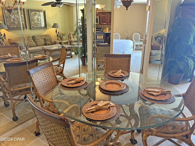 dining space with light tile patterned floors and ceiling fan with notable chandelier