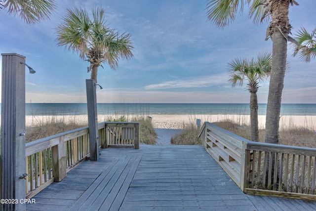 wooden terrace with a water view and a view of the beach