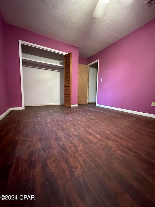 unfurnished bedroom featuring dark hardwood / wood-style flooring, ceiling fan, a closet, and a textured ceiling