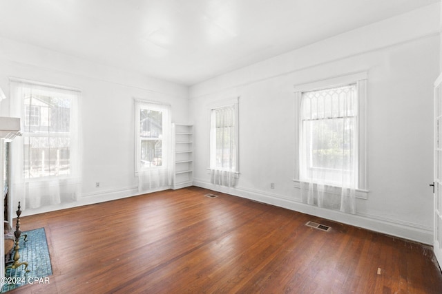 interior space with a wealth of natural light, built in shelves, and wood-type flooring