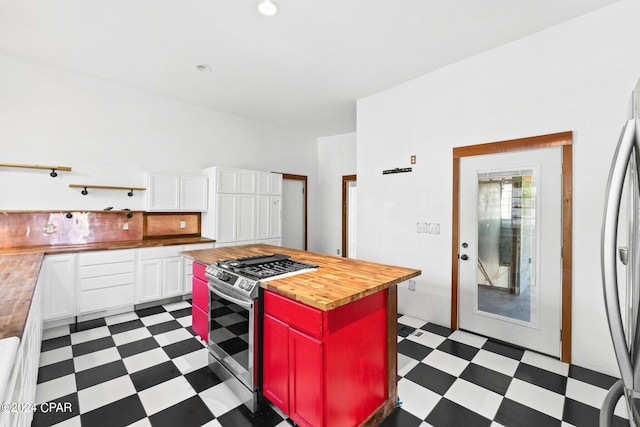 kitchen featuring stainless steel gas range, dark tile floors, white cabinets, and butcher block countertops