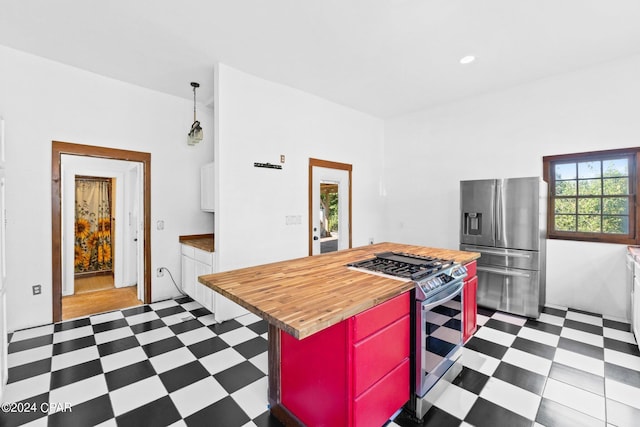 kitchen featuring appliances with stainless steel finishes, dark tile floors, and wood counters