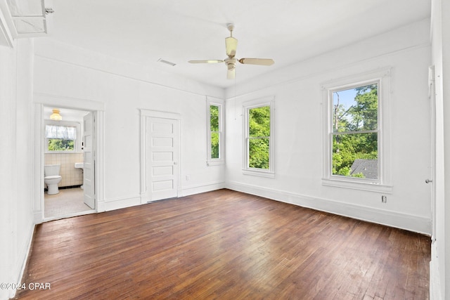 empty room featuring dark hardwood / wood-style flooring, ceiling fan, and a healthy amount of sunlight